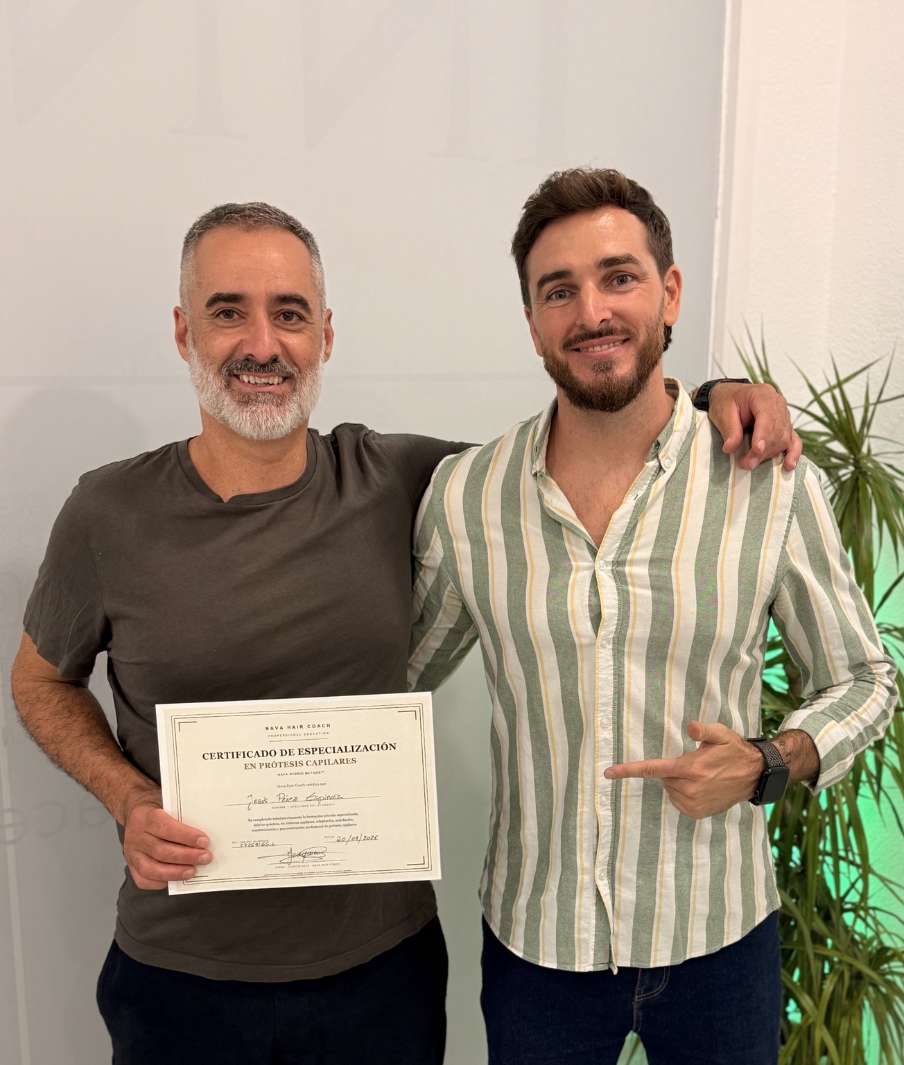 Alumno sosteniendo el certificado de especialización en prótesis capilares junto a Joaquín Nava
